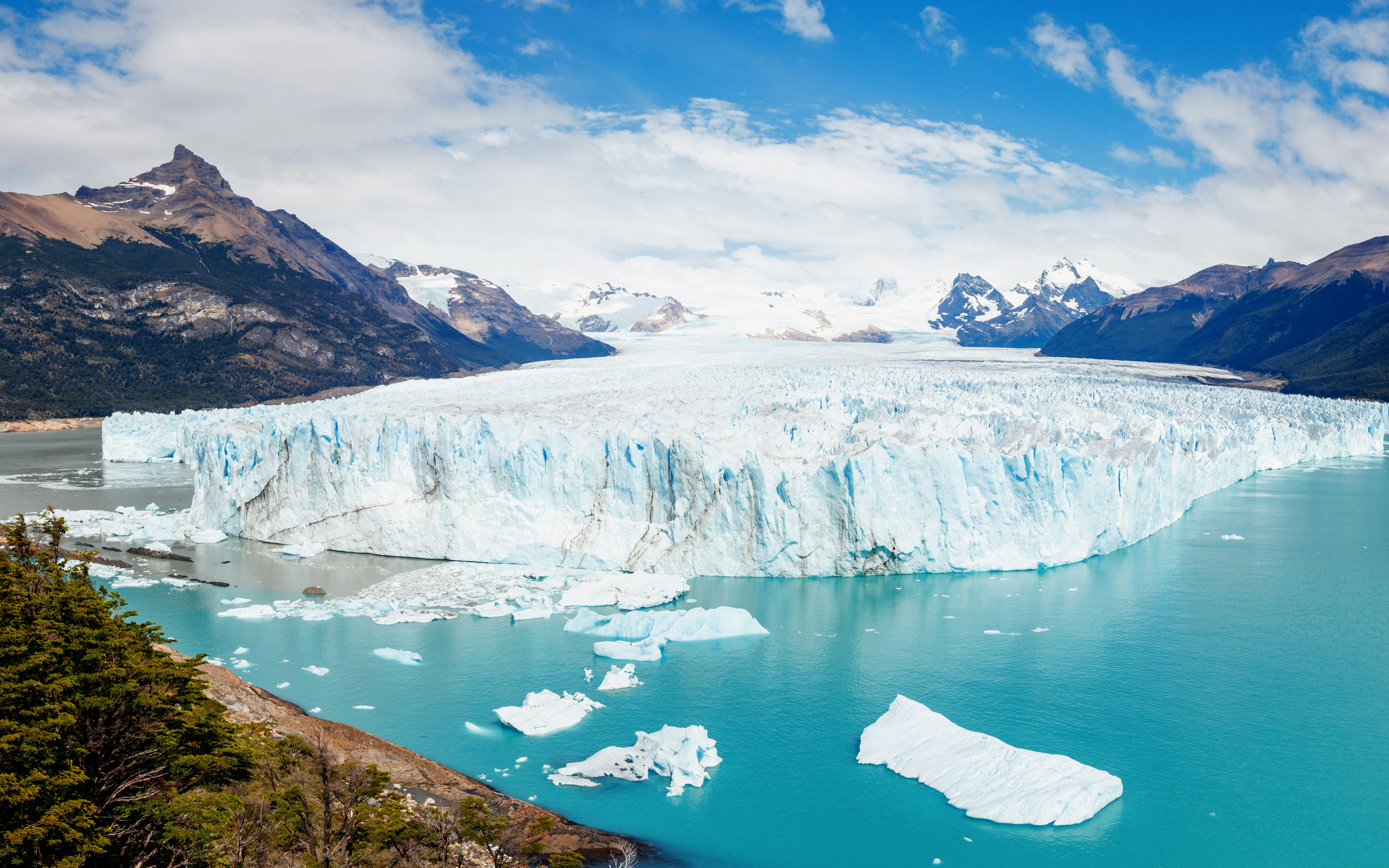 Panoramic view of Perito Moreno Glacier with icebergs and mountains in Los Glaciares National Park, Argentina.