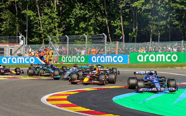 Formula 1 cars racing at the Belgian Grand Prix circuit.