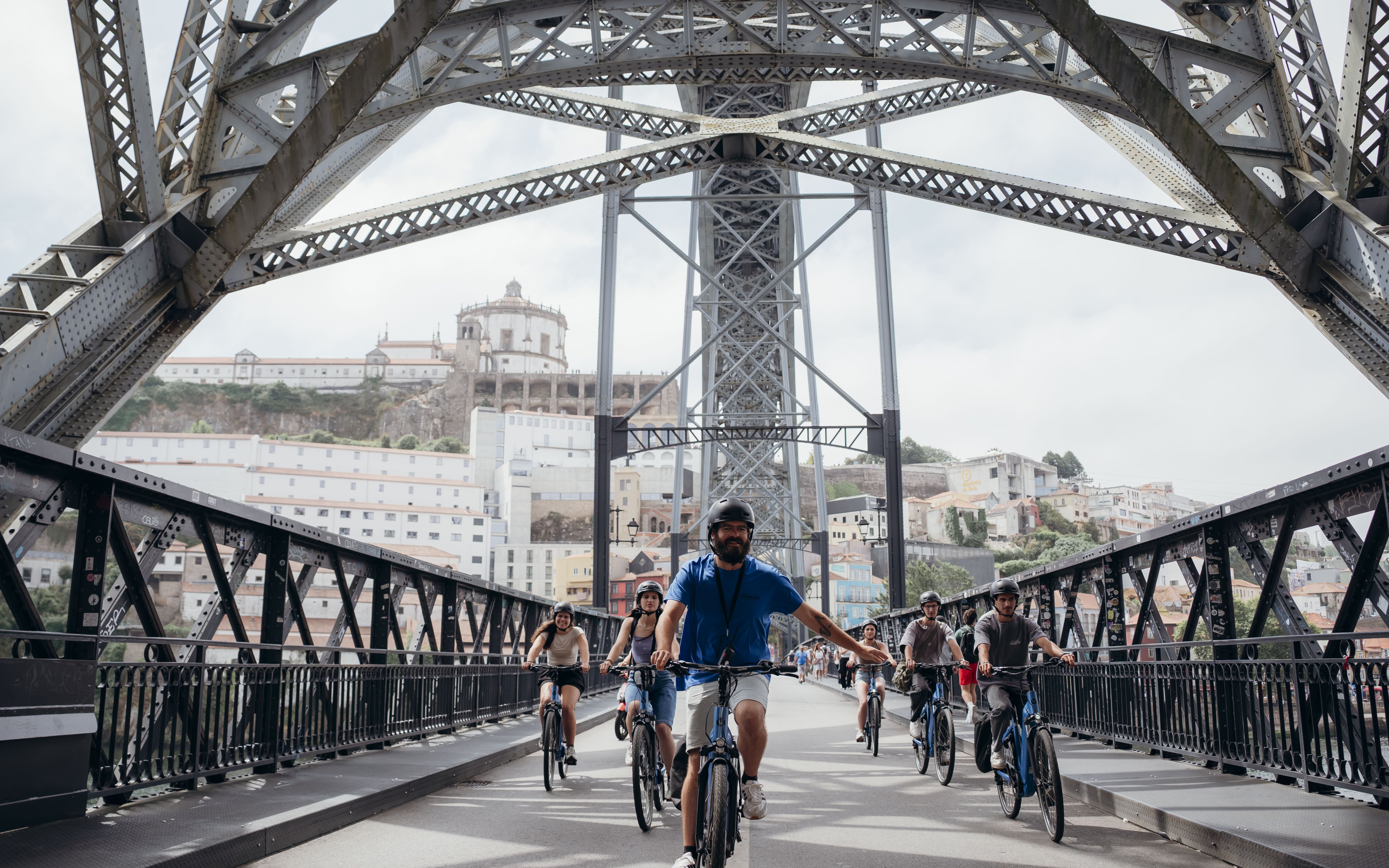 Tourists biking with a guide on Dom Luís I Bridge during Porto highlights tour.