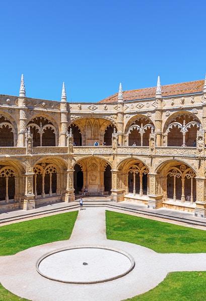 Cloister of the Monastery of Jerónimos in Lisbon, Portugal, showcasing ornate arches and manicured lawn.