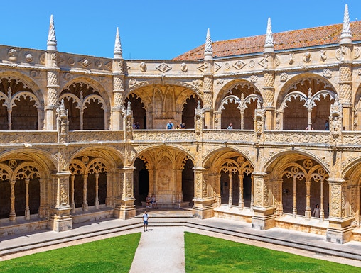 Cloister of the Monastery of Jerónimos in Lisbon, Portugal, showcasing ornate arches and manicured lawn.