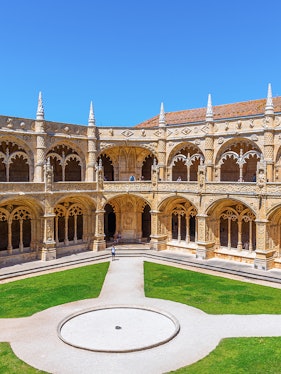 Cloister of the Monastery of Jerónimos in Lisbon, Portugal, showcasing ornate arches and manicured lawn.
