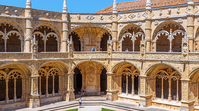 Cloister of the Monastery of Jerónimos in Lisbon, Portugal, showcasing ornate arches and manicured lawn.