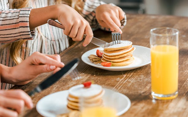 Close-up of fluffy pancakes with syrup drizzling over the stack.