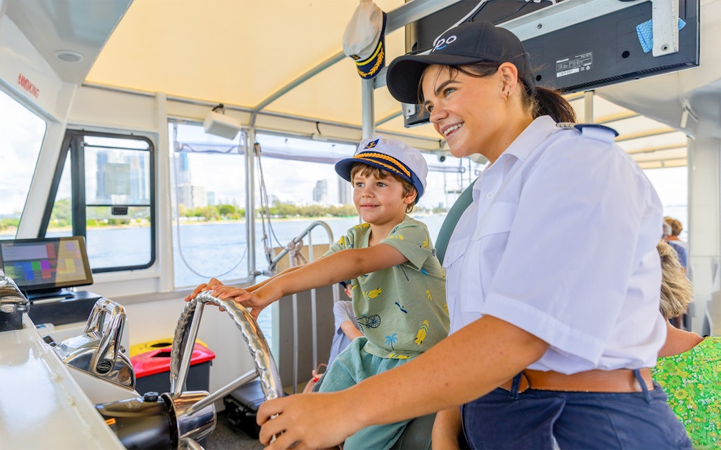 Child steering cruise ship with captain's guidance.