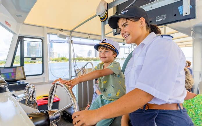 Child steering cruise ship with captain's guidance.