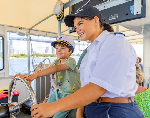Bambino alla guida di una nave da crociera con l'assistenza del capitano.
