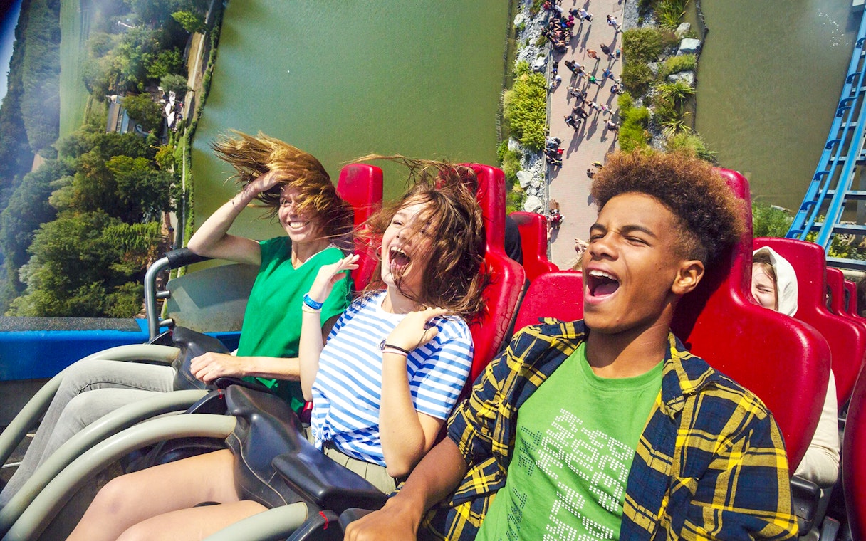 People enjoying a thrilling roller coaster ride with a scenic view below.