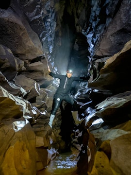 Caver exploring narrow passage in Okohua Glowworm Cave, Waitomo Experience tour.