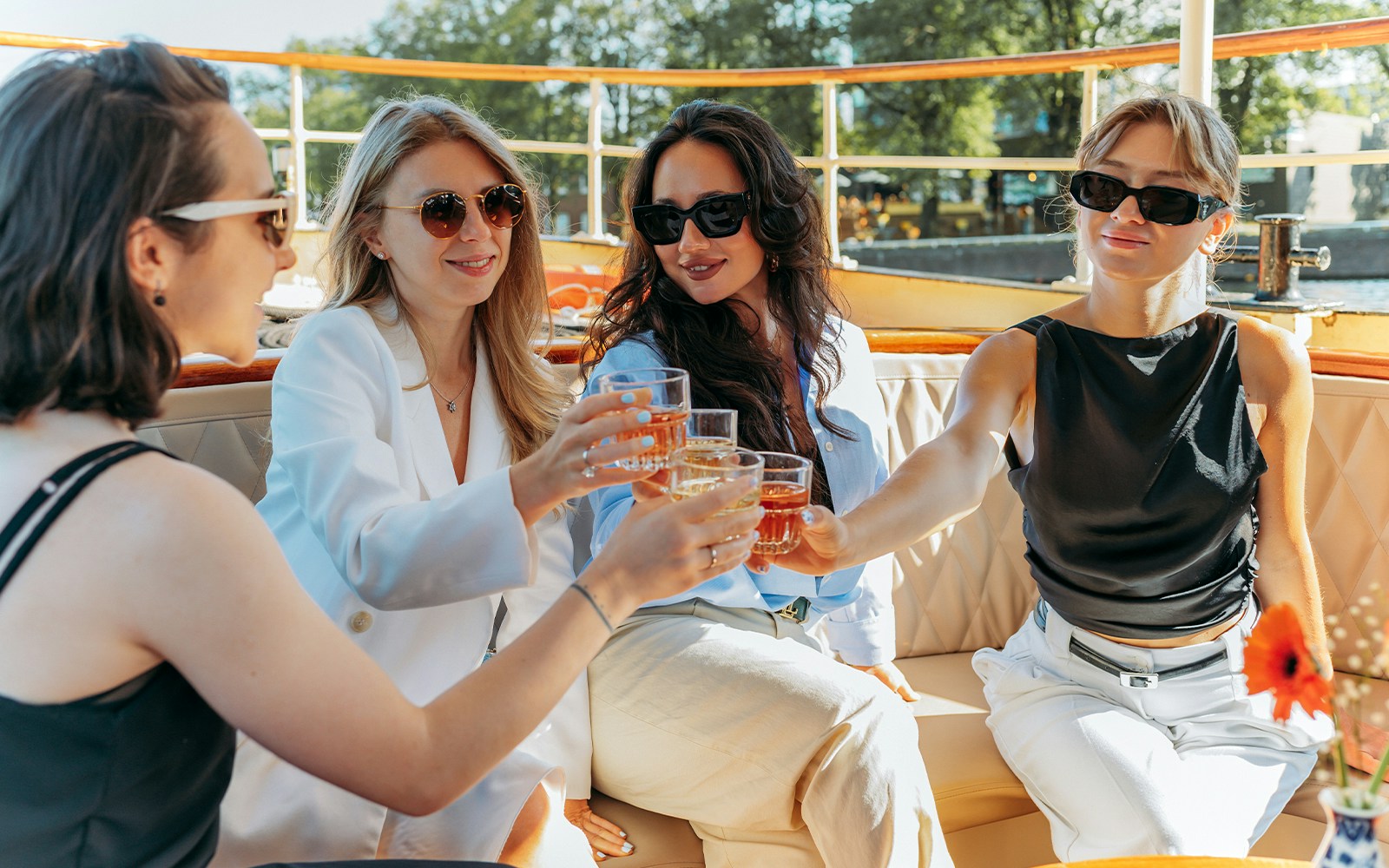 Tourists enjoying drinks on a cruise ship deck with city skyline in the background.