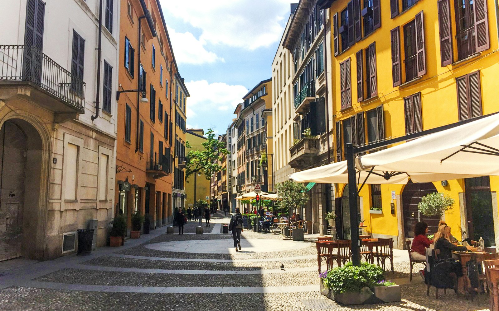 Brera District street with colorful buildings and outdoor cafes in Milan.