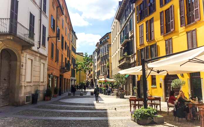 Brera District street with colorful buildings and outdoor cafes in Milan.