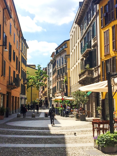 Brera District street with colorful buildings and outdoor cafes in Milan.