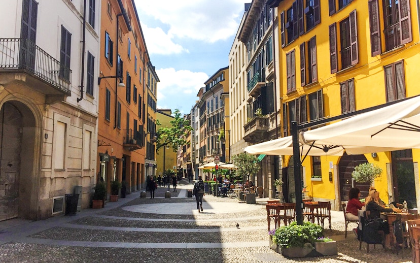 Brera District street with colorful buildings and outdoor cafes in Milan.