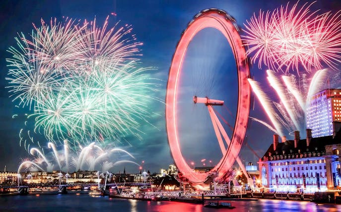 London Eye with fireworks display during New Year's celebration.