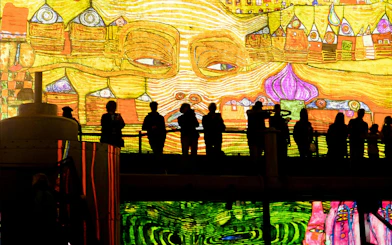 Visitors viewing vibrant digital art at Fabrique des Lumières exhibition.
