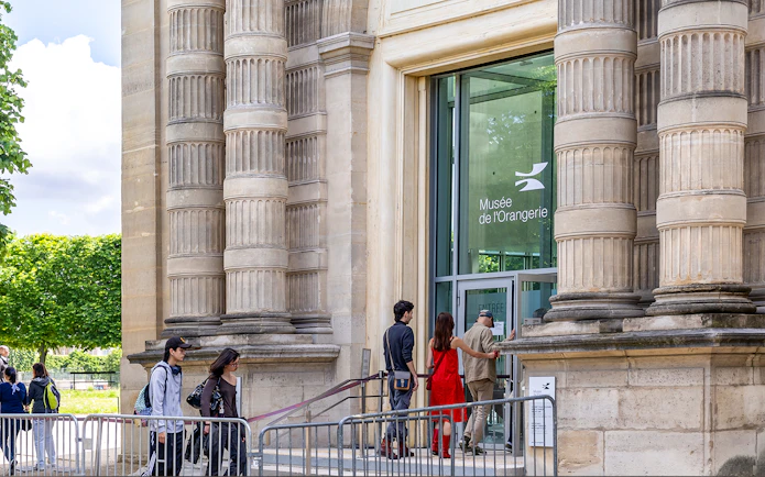 Visitors entering Musée de l'Orangerie, Paris, with its distinctive columned exterior.