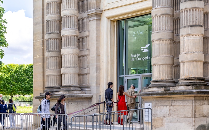 Visitors entering Musée de l'Orangerie, Paris, with its distinctive columned exterior.