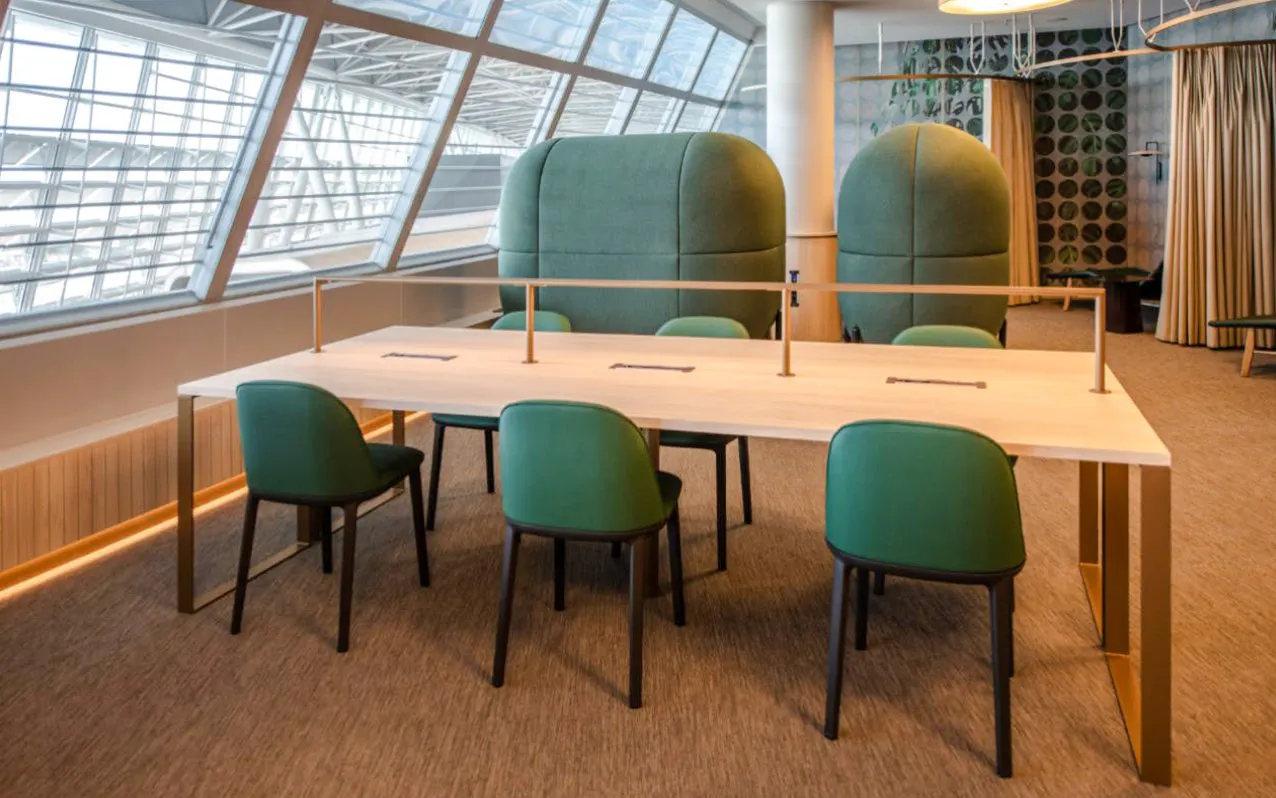 Seating area in Marhaba Lounge at Zurich Airport Airside Centre with green chairs and large windows.