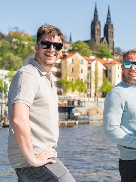 Group of friends on a speed boat with Prosecco, Prague Castle in background.