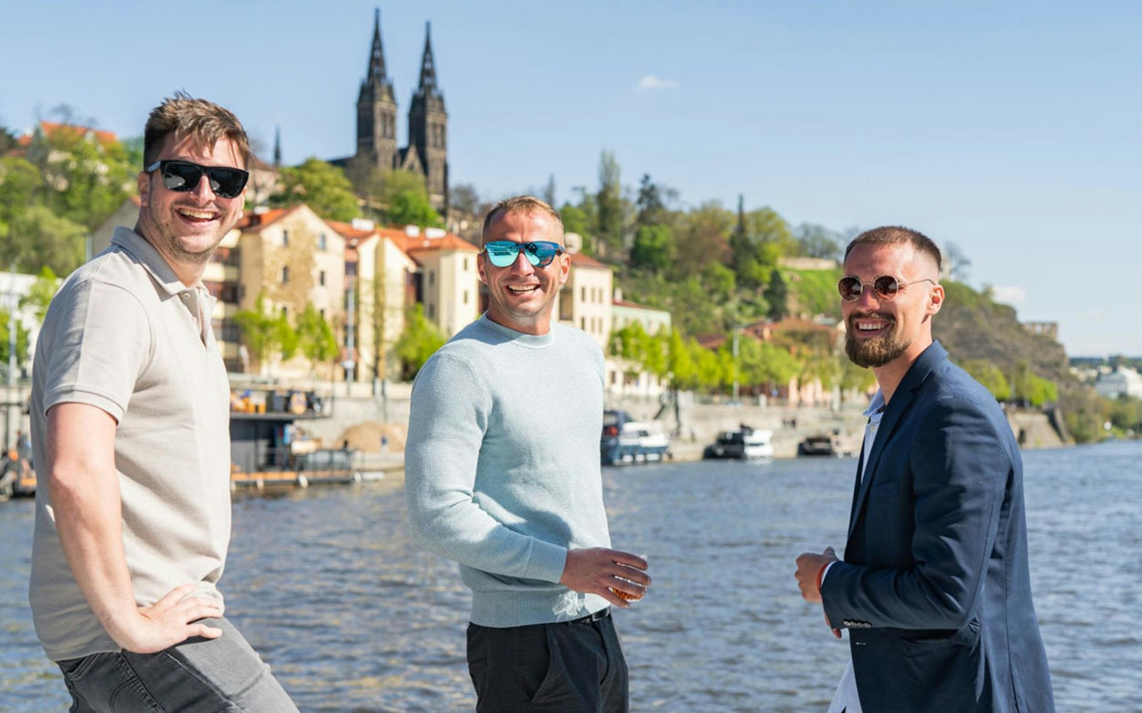 Group of friends on speed boat with Prosecco, with Prague Castle in background.