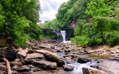 Waterfall cascading over rocks surrounded by lush greenery in Chiang Mai.