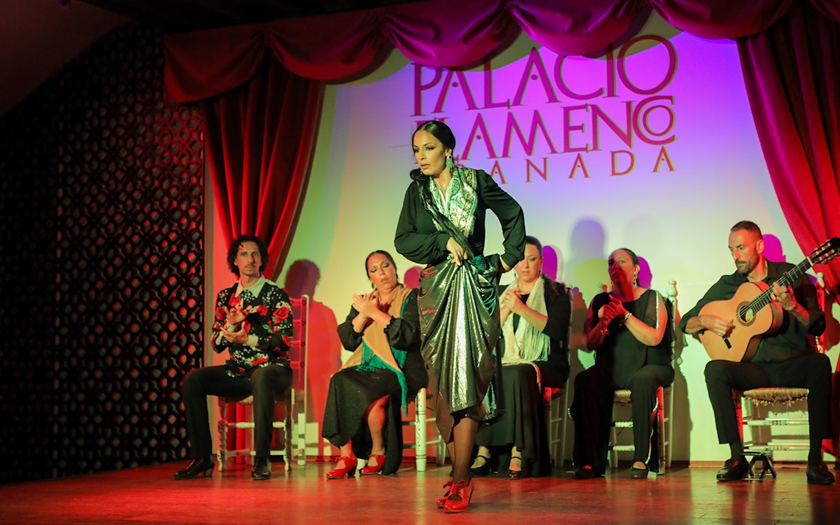 Flamenco dancer performing at Palacio de los Olvidados, Granada, with musicians in the background.