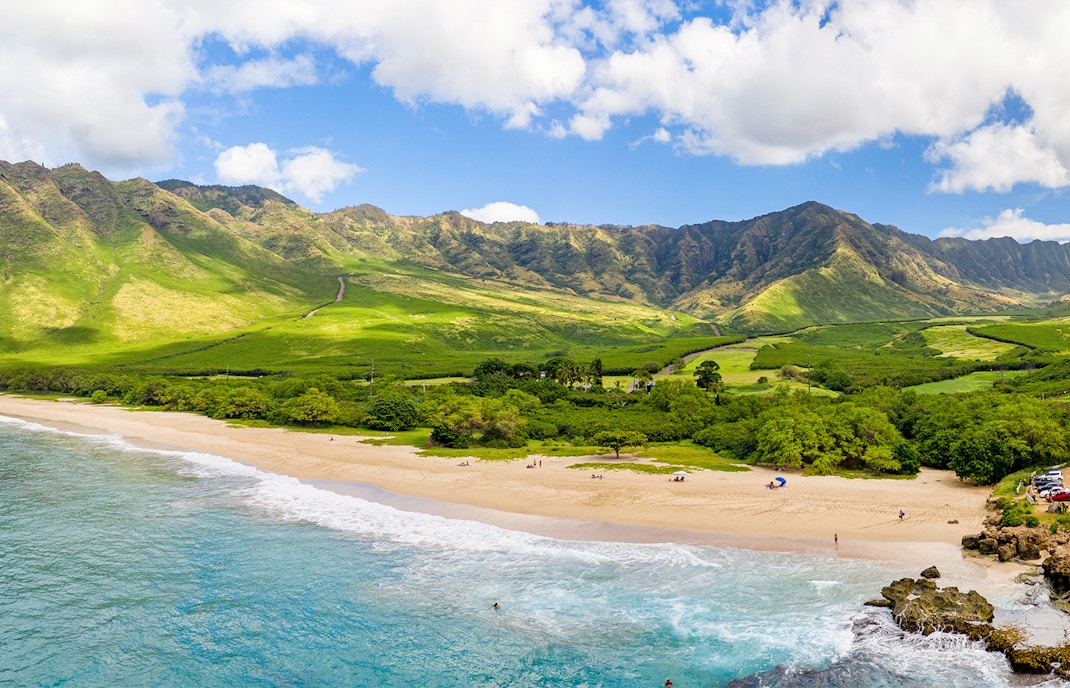 Aerial view of a beach and lush mountains on the west coast of Oahu, Hawaii.