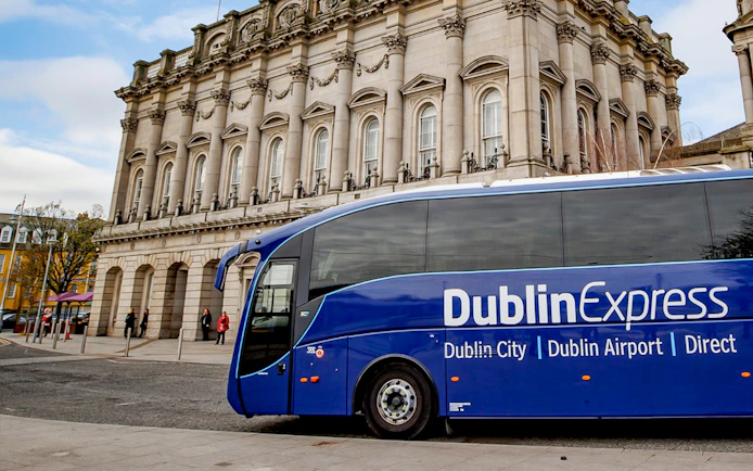 Blue Dublin Express bus in front of historic building, Dublin Airport transfer.
