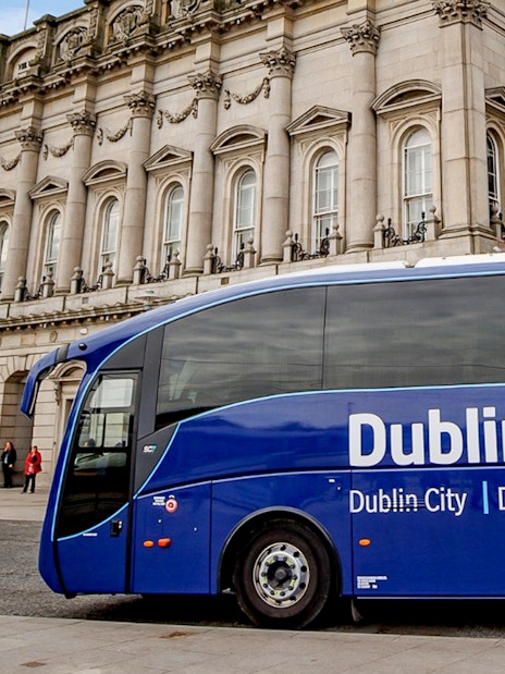 Blue Dublin Express bus in front of historic building, Dublin Airport transfer.