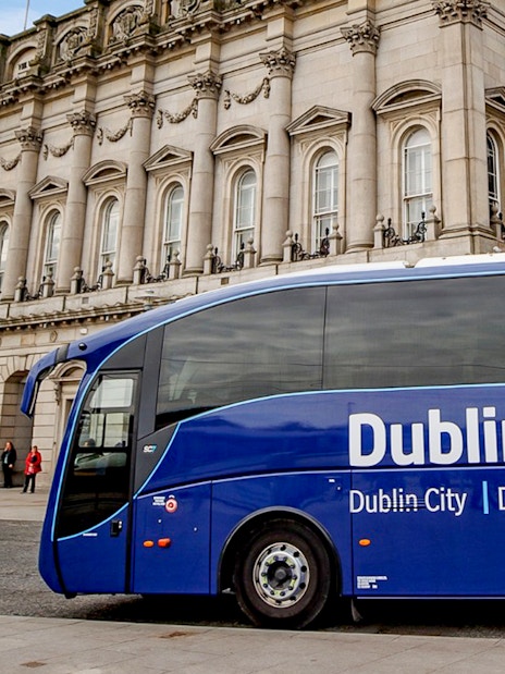 Blue Dublin Express bus in front of historic building, Dublin Airport transfer.