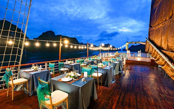 Dinner setup on outdoor deck with string lights and ocean view.