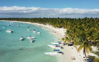 Boats anchored near palm-lined beach on Saona Island, Dominican Republic.
