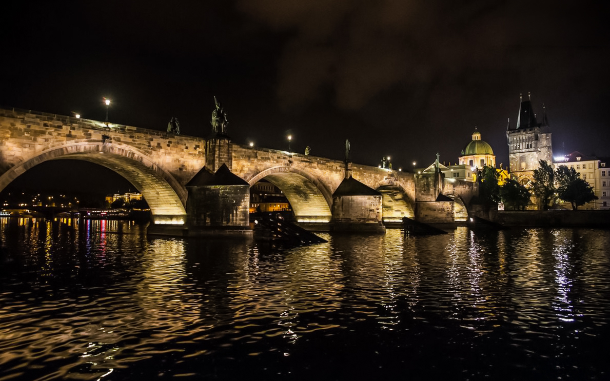 Charles Bridge illuminated at night during a boat party on the Vltava River, Prague.