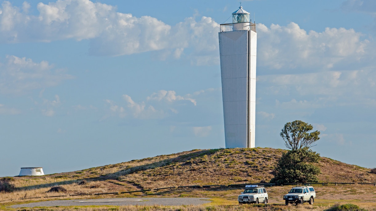 Cape Jervis Lighthouse on a hill with two vehicles, Kangaroo Island, Australia.