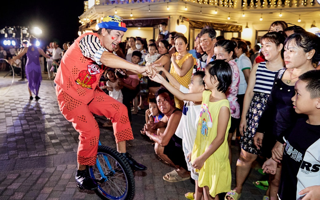 Performer on unicycle interacting with audience at Phu Quoc Island cultural event.