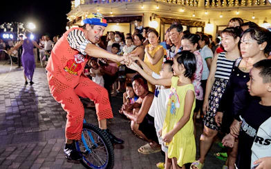 Performer on unicycle interacting with audience at Phu Quoc Island cultural event.