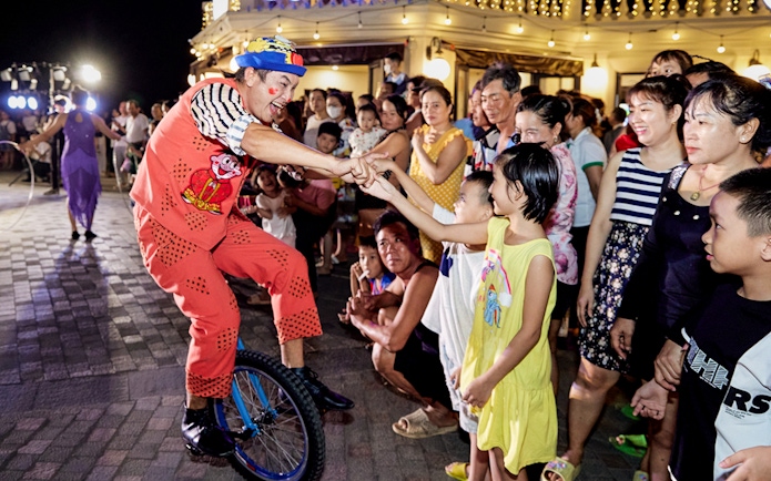 Performer on unicycle interacting with audience at Phu Quoc Island cultural event.