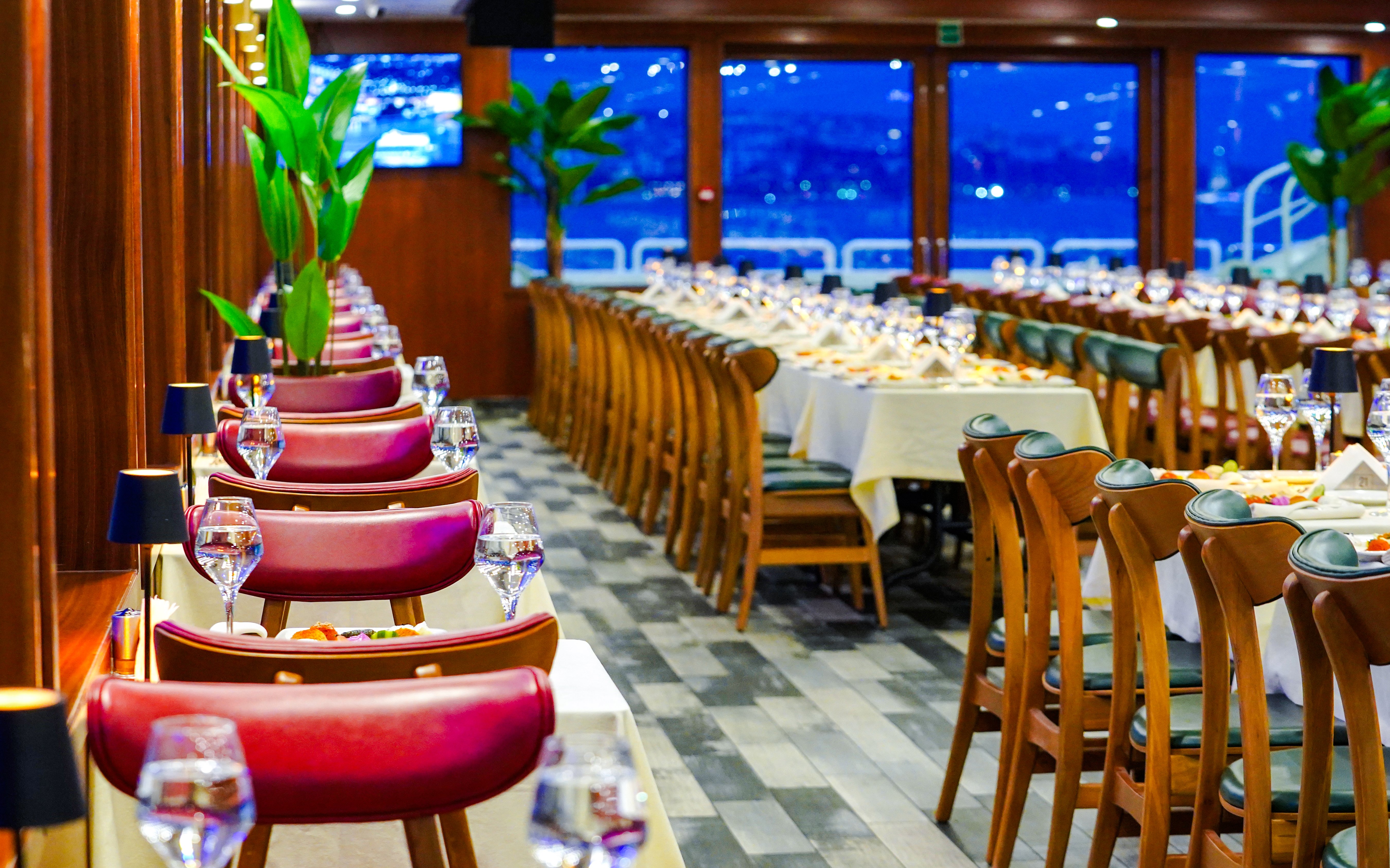 Tables set for dining on Bosphorus Lunch Cruise with city view through windows.