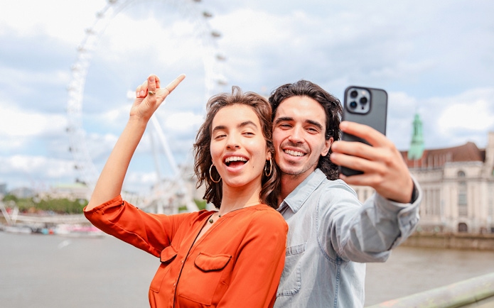 Couple taking a selfie with the London Eye in the background during a champagne experience.