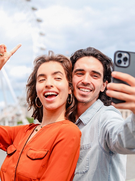 Couple taking a selfie with the London Eye in the background during a champagne experience.