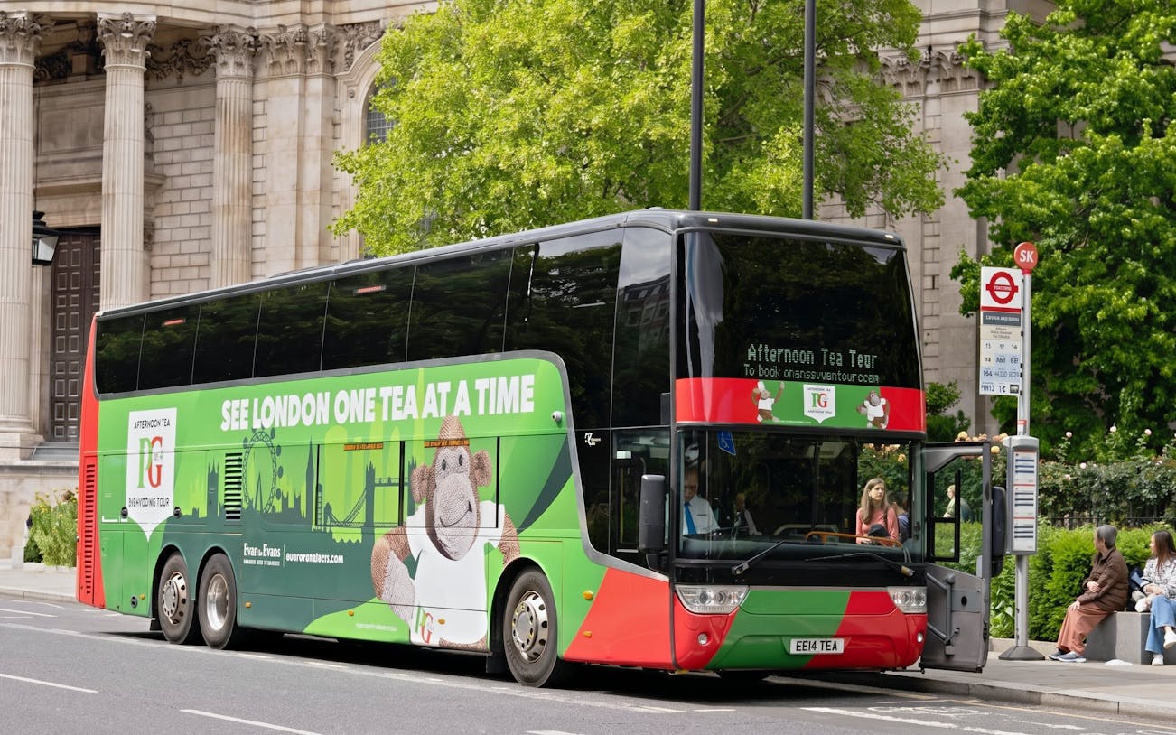 Double-decker bus for Classic London Sightseeing Tour parked near historic building.