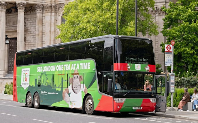 Double-decker bus for Classic London Sightseeing Tour parked near historic building.