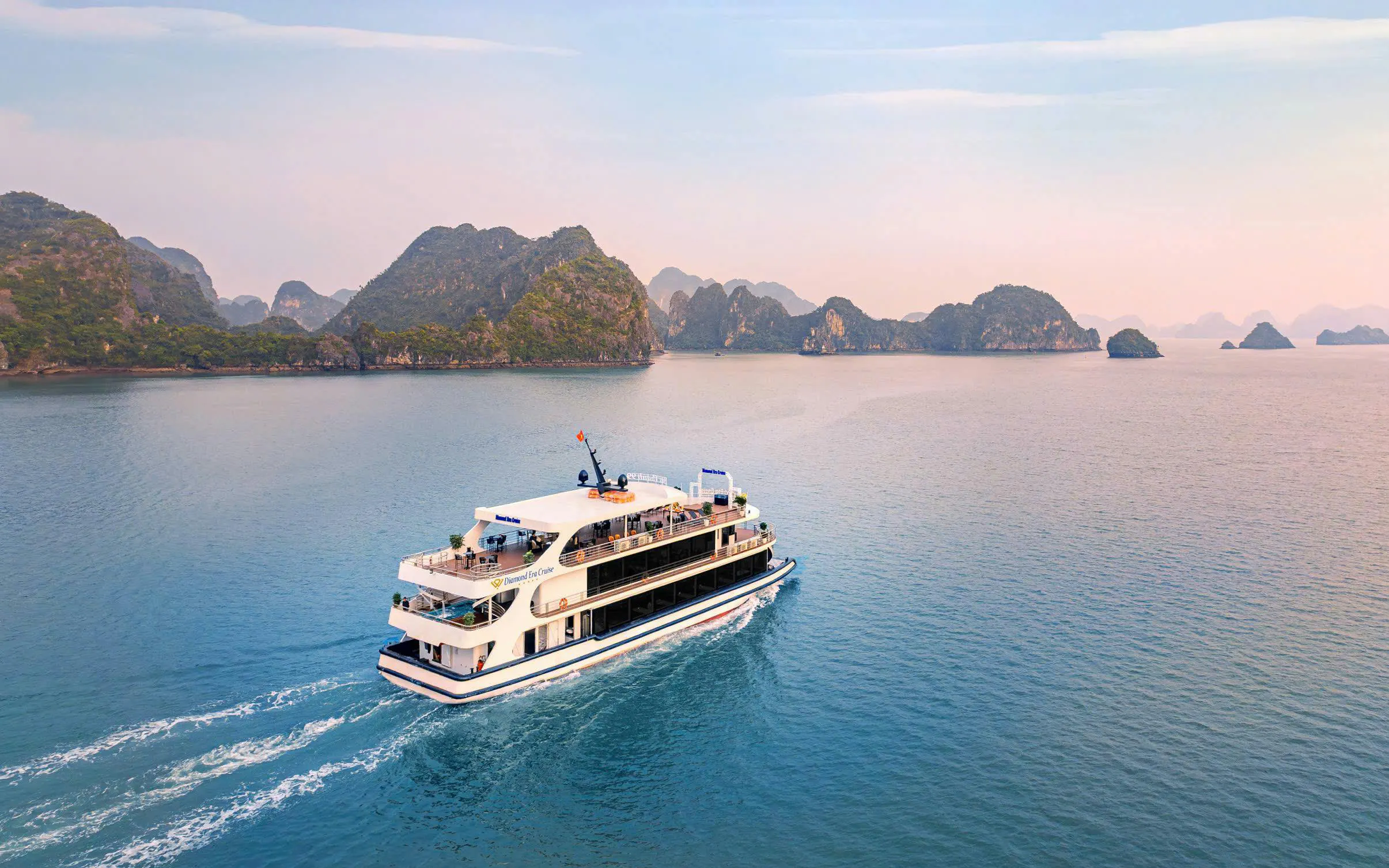 Luxury cruise ship sailing in Ha Long Bay with limestone islands in the background.