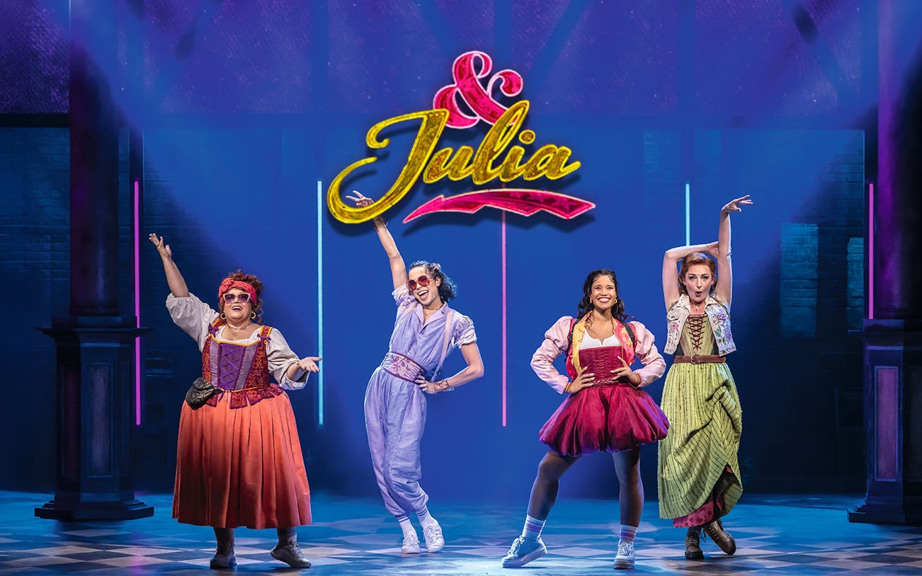 Performers on stage in colorful costumes under the "&Julia" sign.