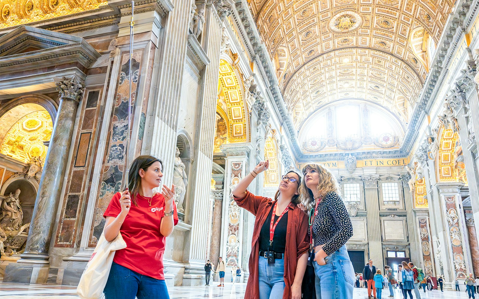St. Peter's Basilica interior with visitors on a guided tour in Vatican City.