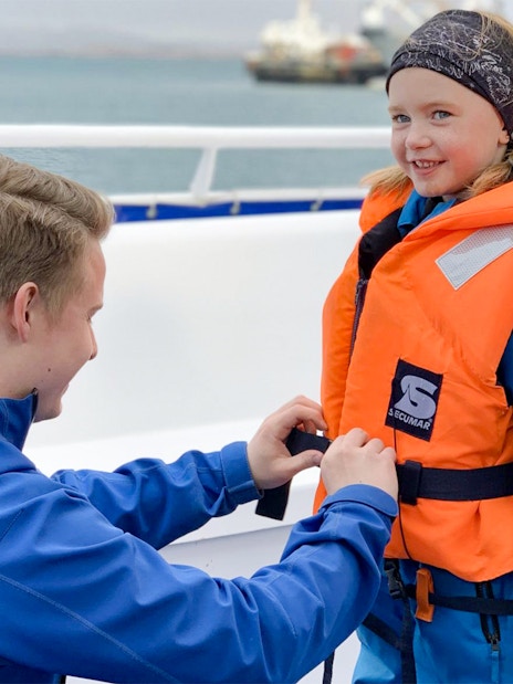 Guide assisting child with safety gear on Akureyri Whale Watching tour, Iceland.