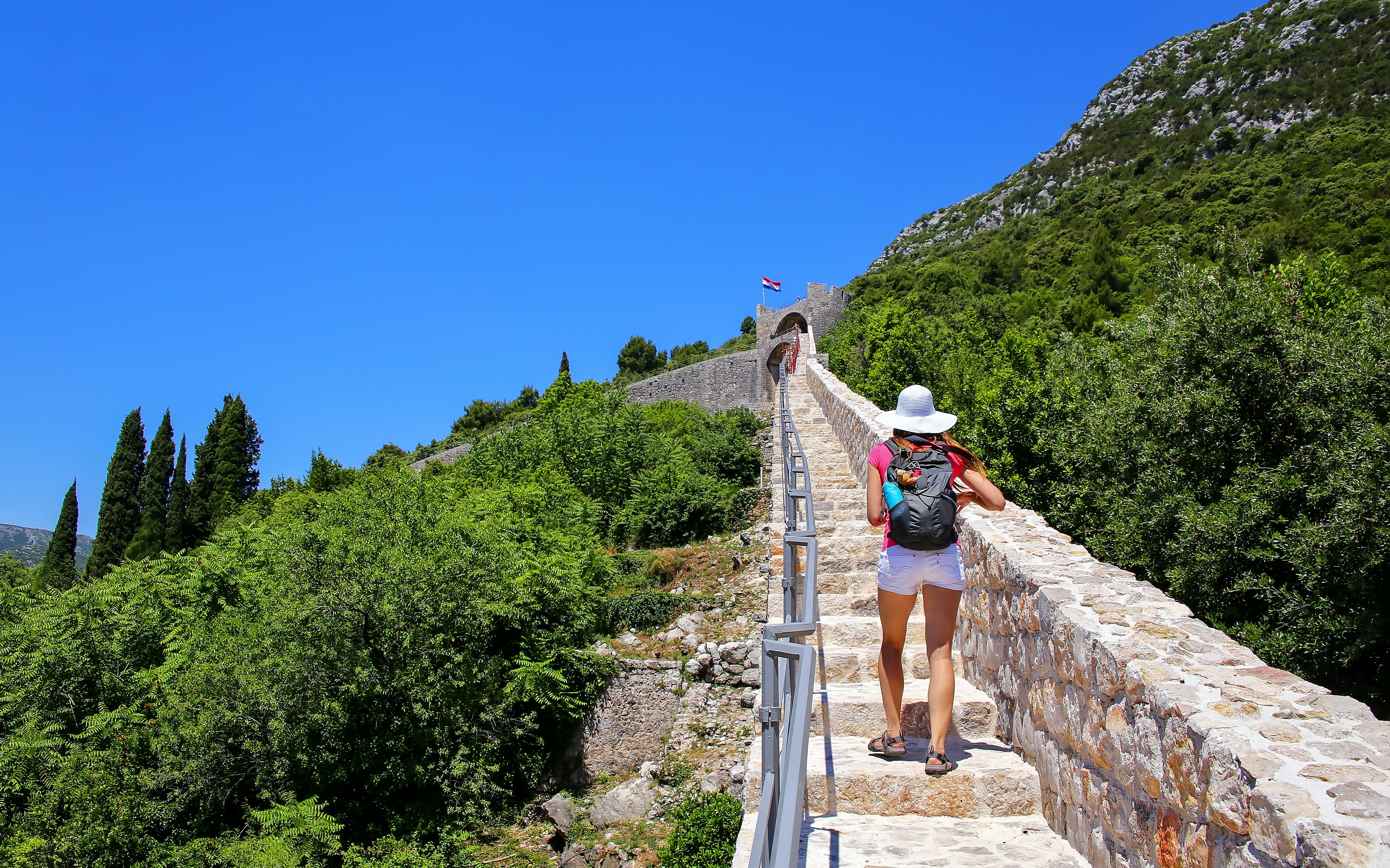 Young woman walking along the stone wall of Ston, Peljesac Peninsula, Croatia.