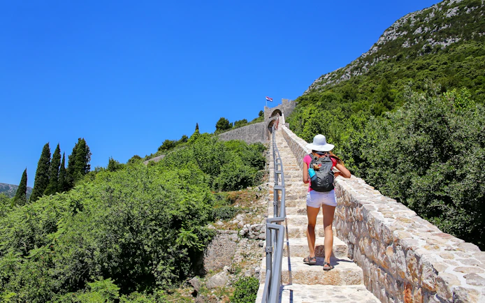 Young woman walking along the stone wall of Ston, Peljesac Peninsula, Croatia.