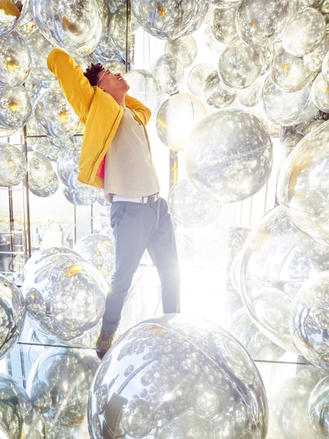 Person inside Air exhibit at SUMMIT One Vanderbilt, surrounded by reflective spheres, New York City.